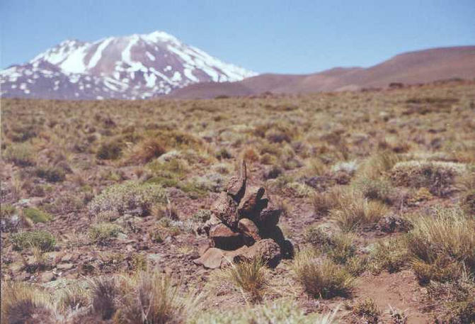 S37W70 Monolito de Piedra mas allá el Volcán Tromen   {stone marker, Tromen Volcano in background}