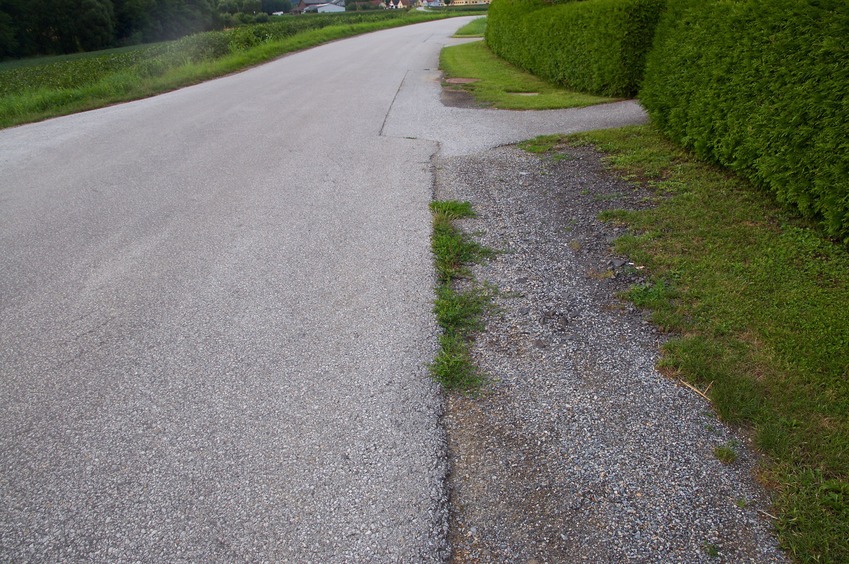 The confluence point lies on a paved road, next to a road of houses