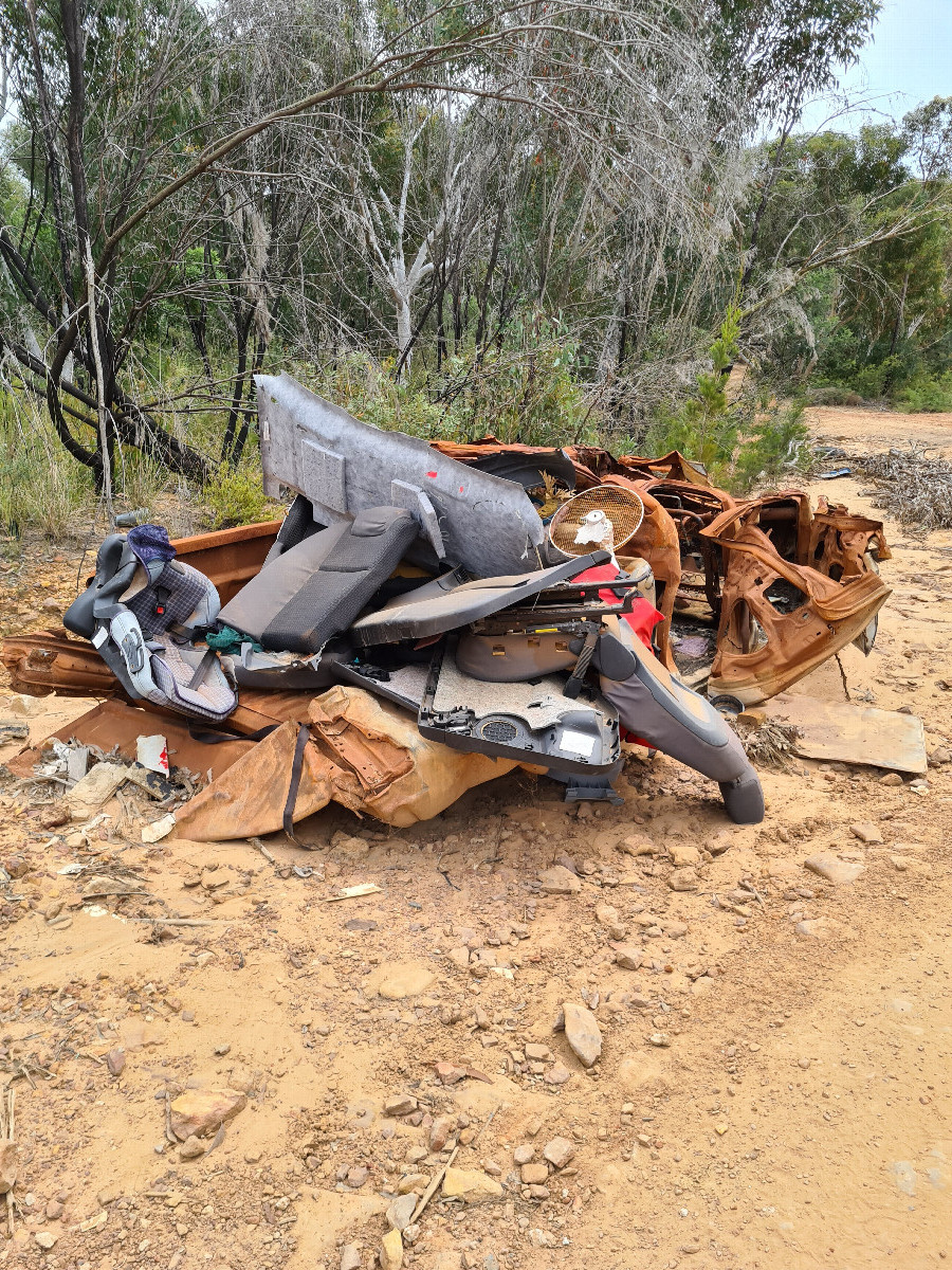 Rusted abandoned car, with some new trash on top