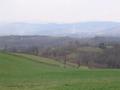 #9: View south from the car: the confluence 180 m down the hill. Snow capped Mount Bjelašnica on the horizon.