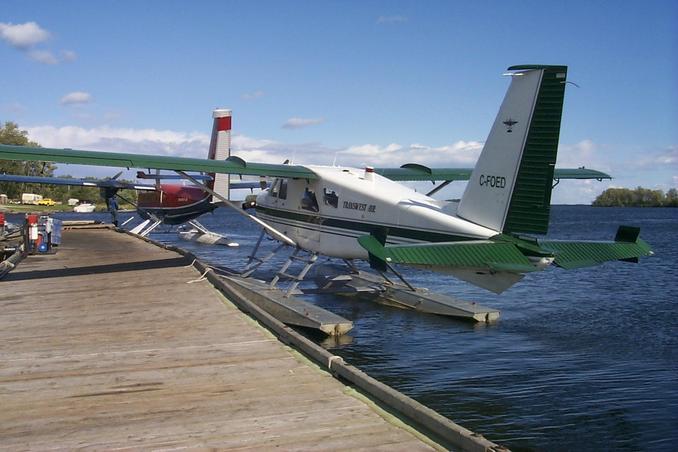 The red and blue plane - a Dehavilland twin otter  - is being loaded with lumber.