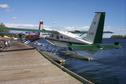 #6: The red and blue plane - a Dehavilland twin otter  - is being loaded with lumber.