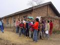 #8: Facing east, with everyone standing on the confluence, at the corner of the brick building