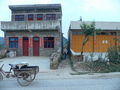 #10: Ah Feng emerges onto the main road between two buildings, with a bean curd hawker's tricycle parked out front. The confluence is 470 metres SSE.