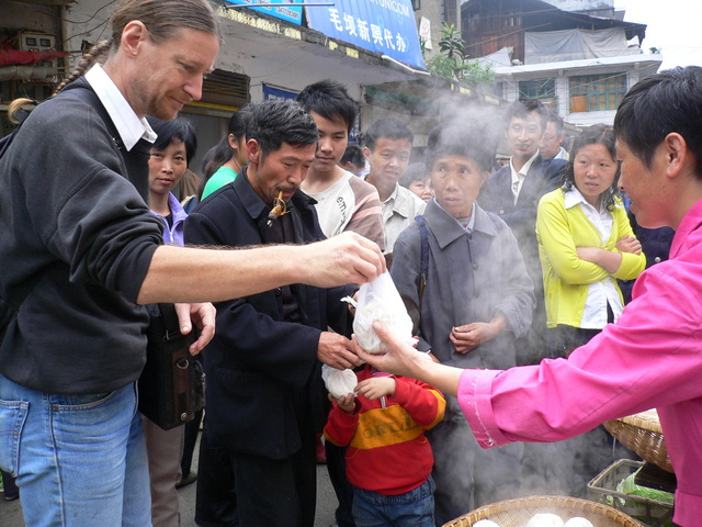 Targ buys some steamed buns for breakfast as curious locals look on.