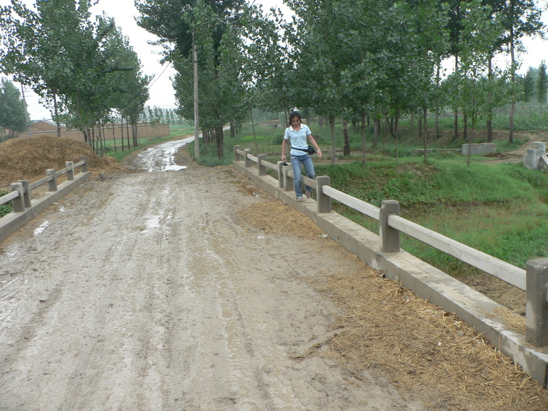 Ah Feng finding the least muddy way across the bridge in Fèiqīnzhuāng Village