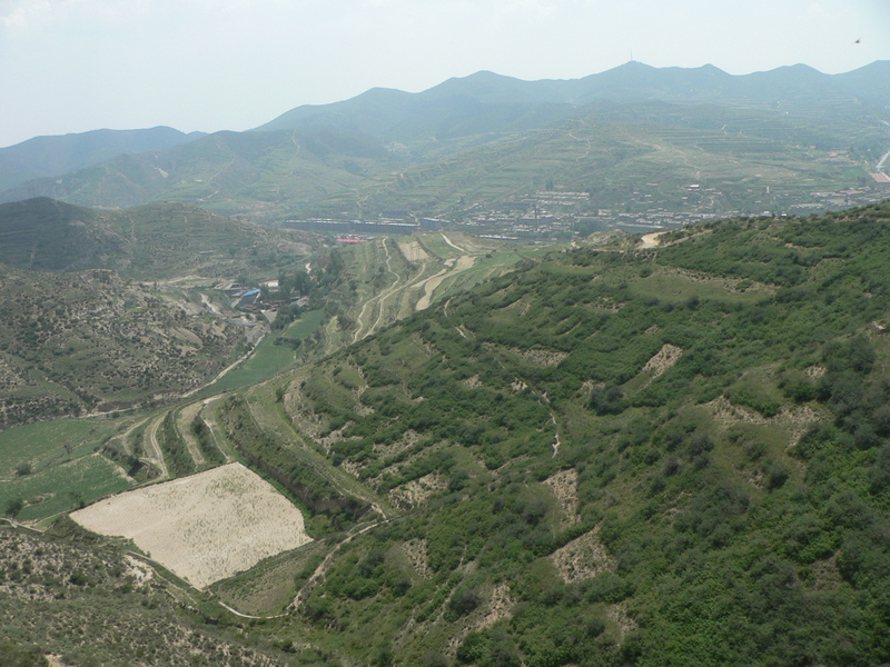 View looking back towards the main road, which is hidden from view, but runs from left to right near the red-roofed building in the distance