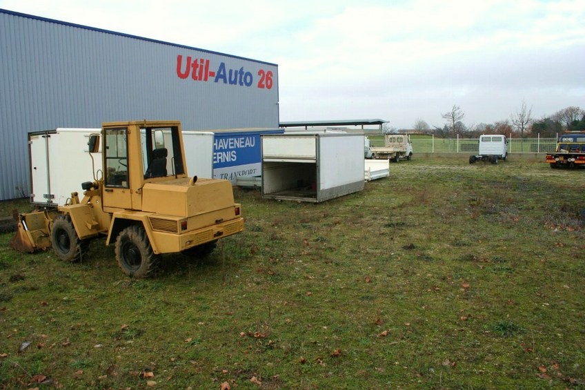 The point, close to the wall near the containers