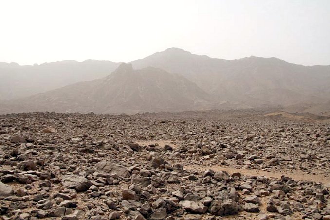 View from the cairn towards the 22N 25E confluence being 150 meters above the plane, on the slope of the gully, at the picture centre. Behind the gully the slopes of the northern Jabal `Uwaynāt ridge.