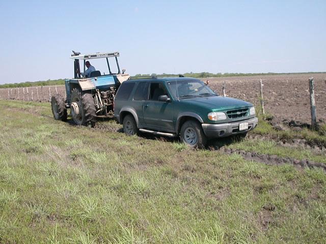 The tractor is removing the truck from mud