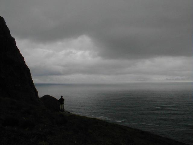 Gjertrud standing on the edge below the confluence. Atlantic ocean to the West and Einevarden to the East,