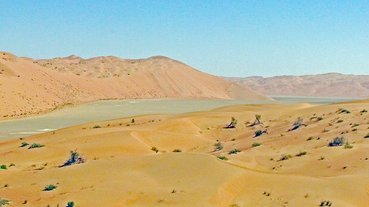 #1: View looking ENE to the confluence area from 700 ft (213 m) distant; The Confluence is located on the sabkha, with a line of dunes just to the North.