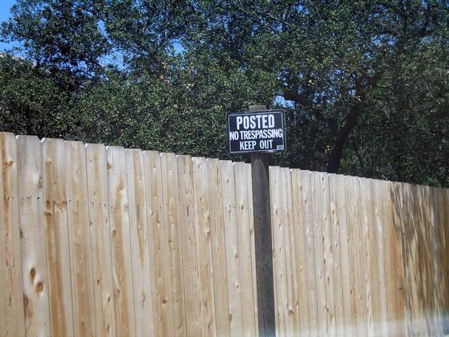 Looking north towards the confluence with the view blocked by a fence and sign