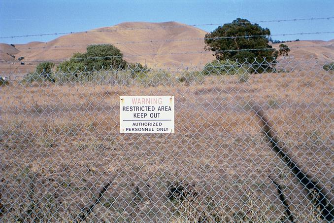 The confluence is located 168 feet beyond this security fence - probably close to the oak tree on the right