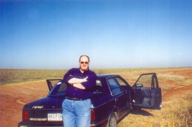 Vic leaning on the car.