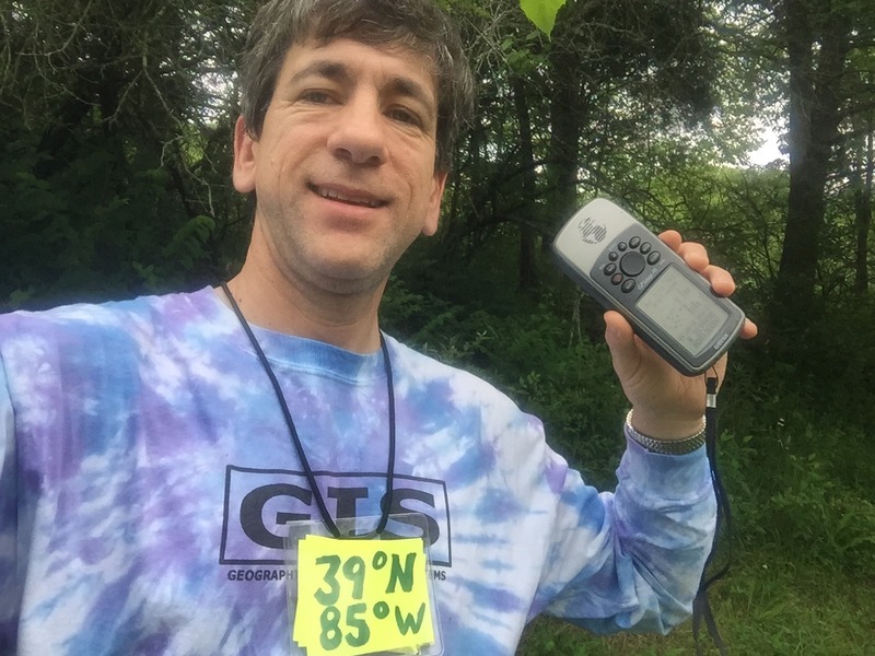 Joseph Kerski at the confluence point with GIS shirt. 