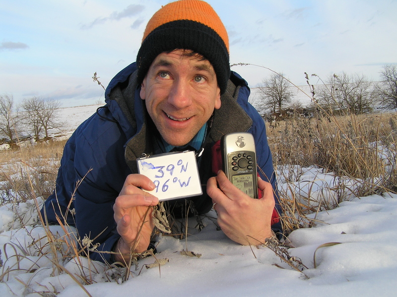 Joseph Kerski lying in the snow and mud at the confluence point.