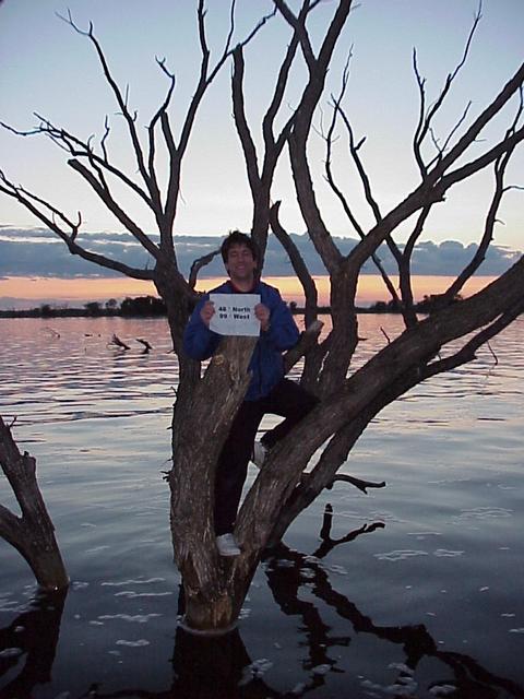  Joseph Kerski holds 48 N 99 W sign in tree submerged by rising water of Devils Lake, approximately 12 meters west of the confluence.