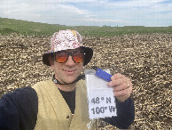 #7: Joseph Kerski at the confluence point with map hat and harmonica.