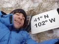 #5: Geographer Joseph Kerski lying on the grass and snow at the confluence site.