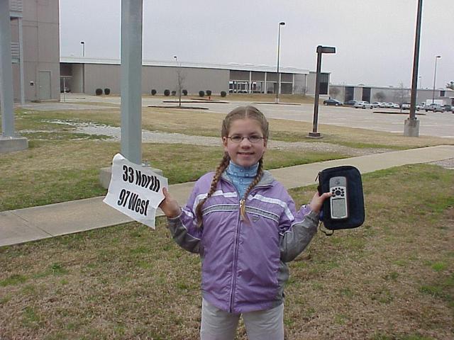 Emily Grace Kerski at the confluence site, GPS and sign in hand.