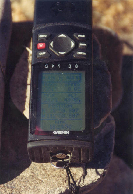 GPS sitting on the rock cairn showing the reading.