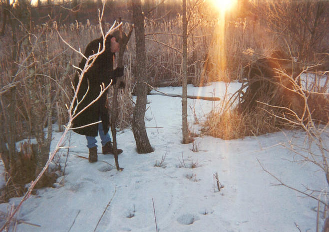 Heading south away from the confluence, Tom pauses to look into the murky marsh water through a small hole in the ice.