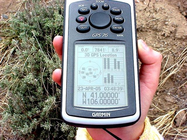 Lilia's hand holding the GPS receiver at the confluence site.