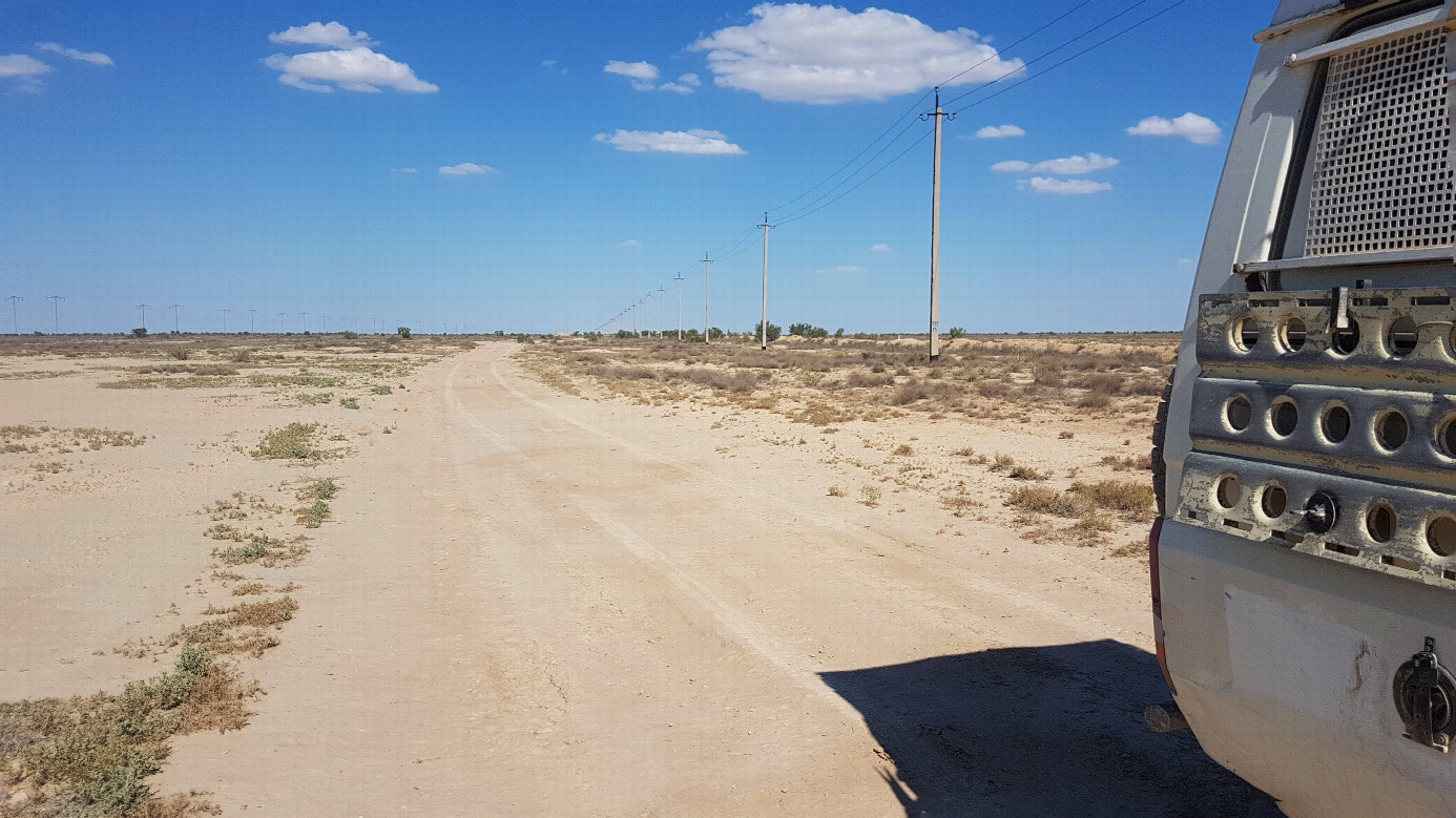 a bumpy hard clay road follows the power lines