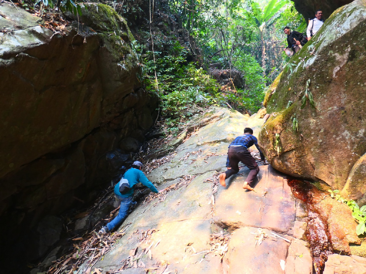 Climbing a slippery rock wall with running spring water